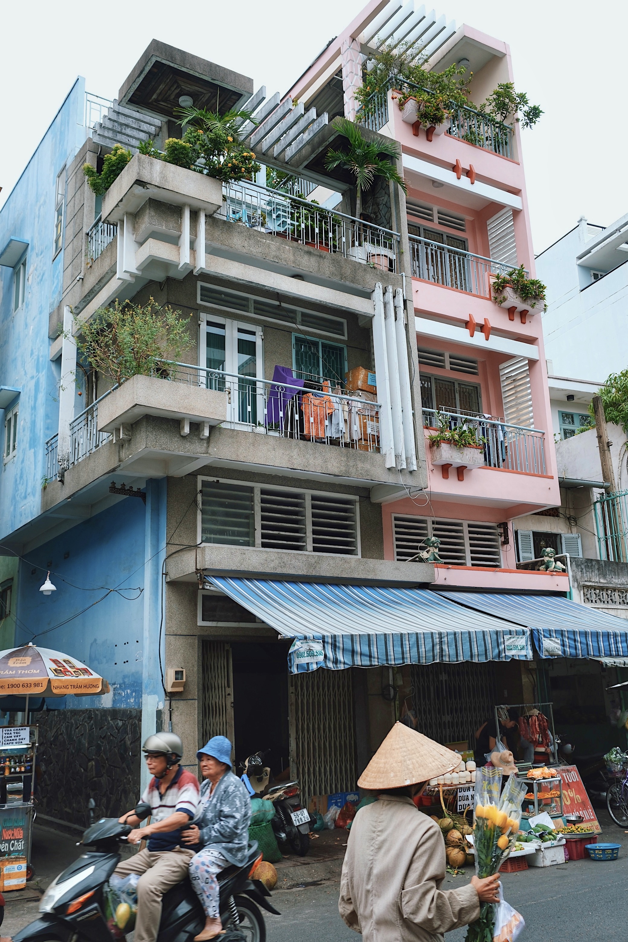 A colorful street in Ho Chi Minh City showcasing 2 modernist houses with clean lines and tropical adaptations such as brise soleils.
