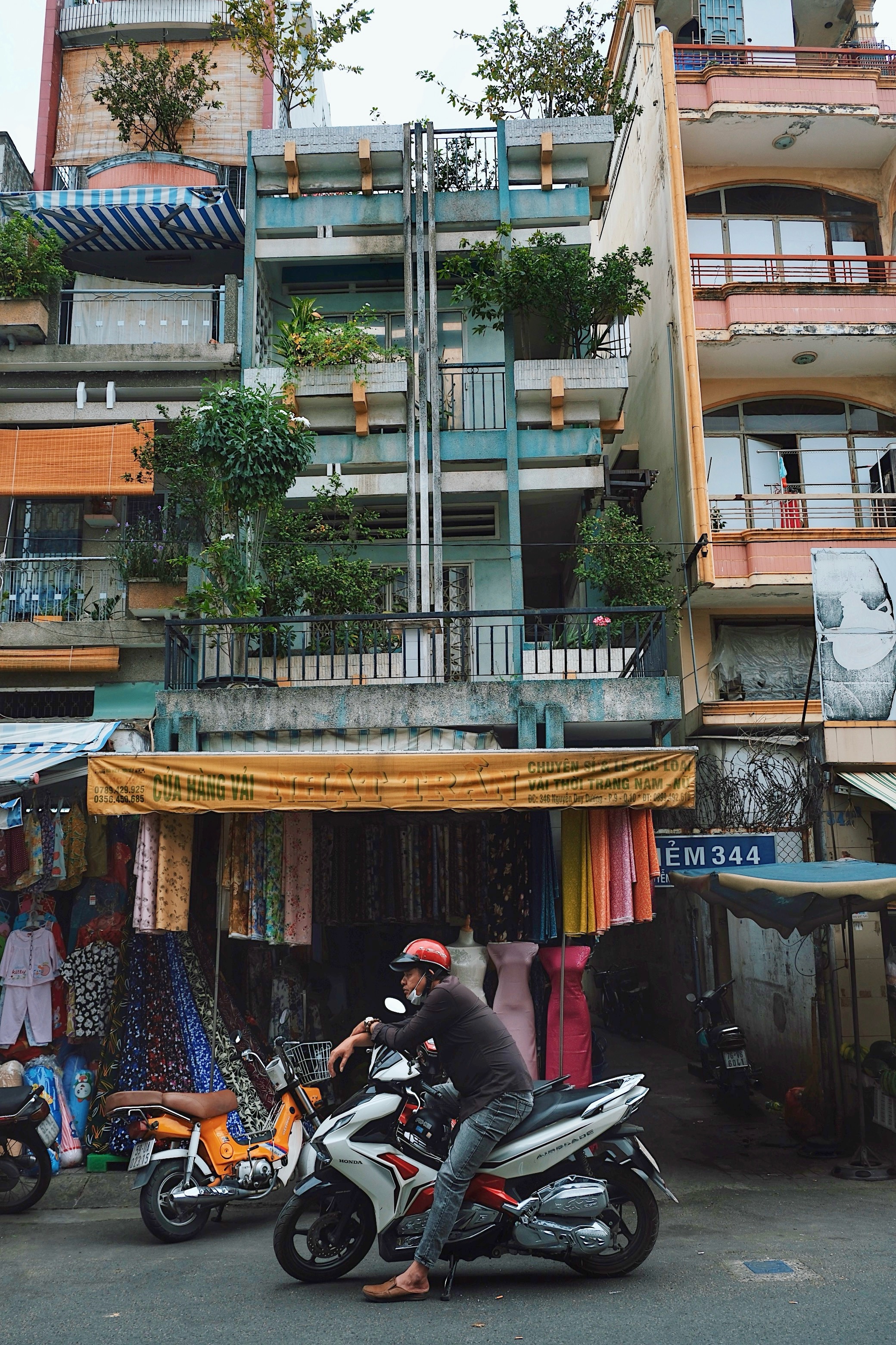 Everyday life in Ho Chi Minh City, Vietnam: A motorbike parked in front of a blue modernist shophouse with vertical concrete brise soleils.
