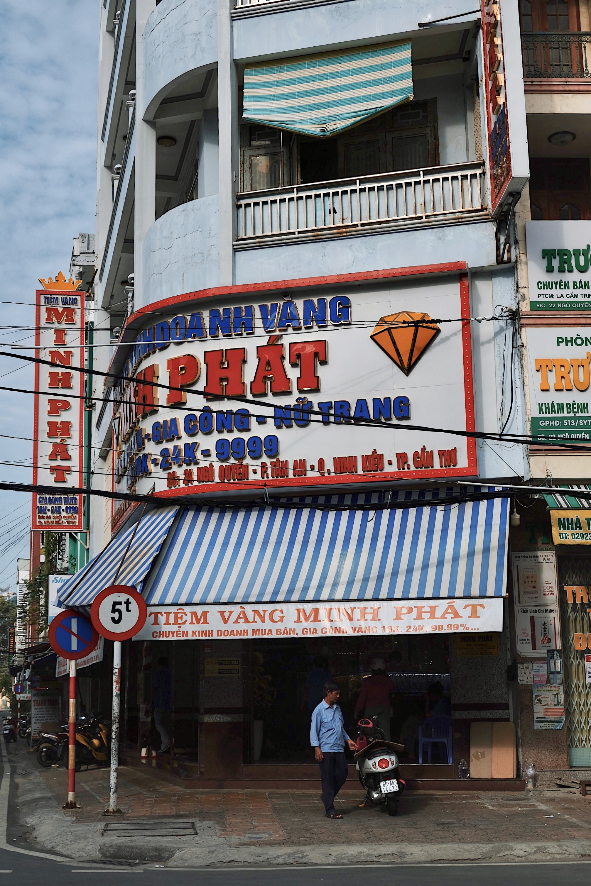 A Vietnamese jewelry store in Cần Thơ with oversized, bold, and ostentatious commercial signage, reflecting the city's eclectic urban aesthetic