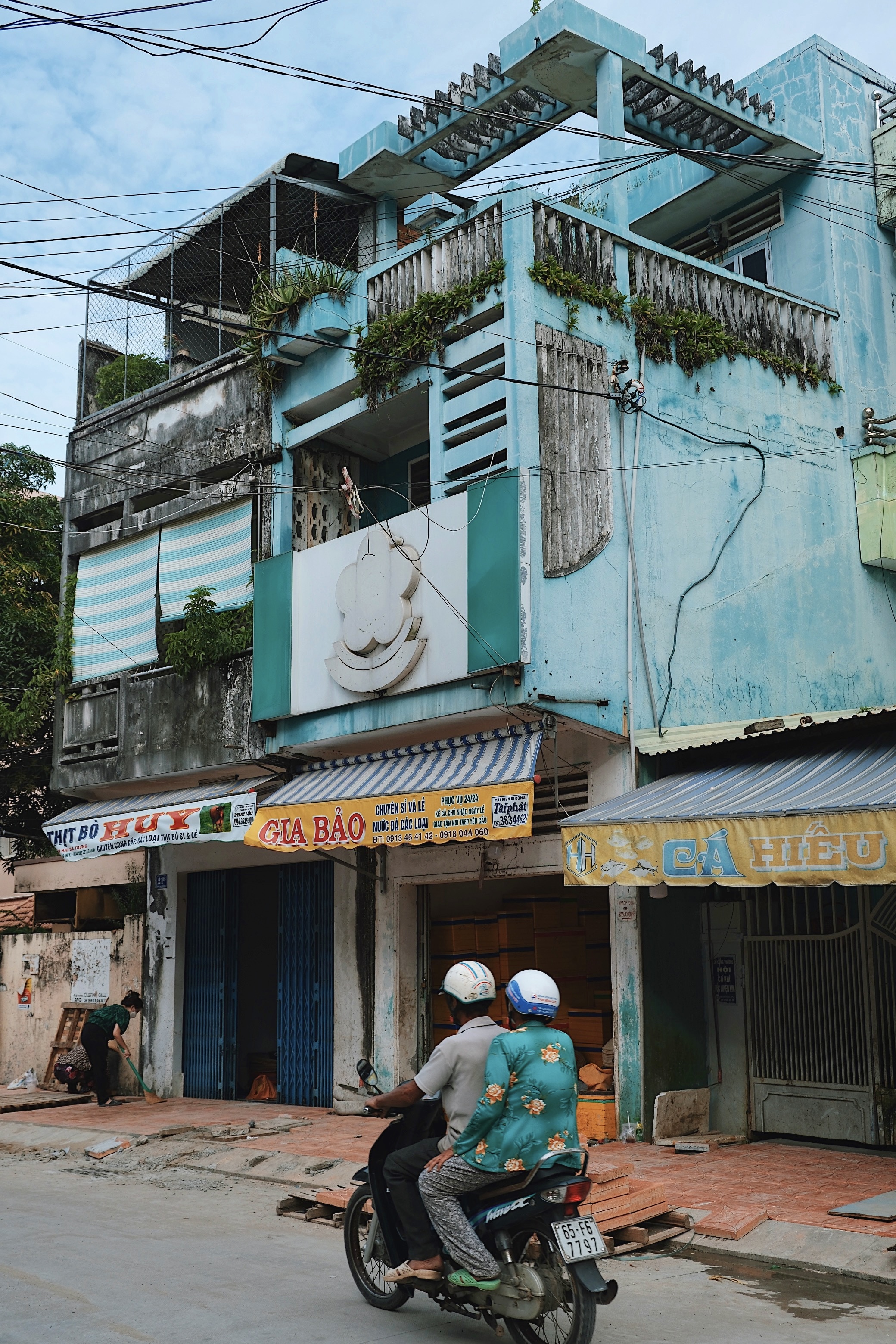 A motorbike in Can Tho matching the vibrant blue facade of a modernist house, reflecting spontaneous color harmony in Vietnamese streets.