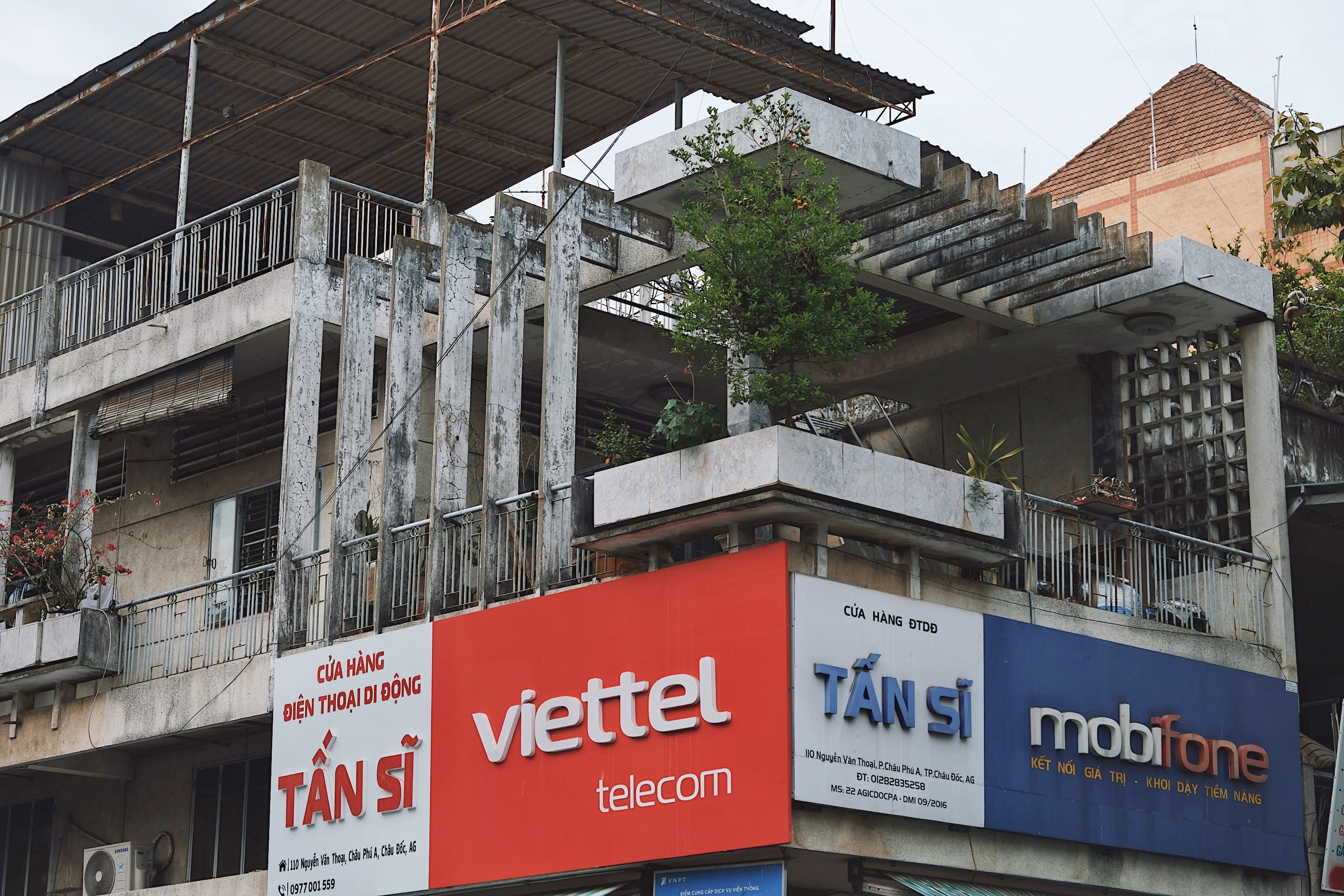 South Vietnamese modernist apartments in Chau Doc with raw concrete textures, patterned ventilation blocks, and integrated greenery.