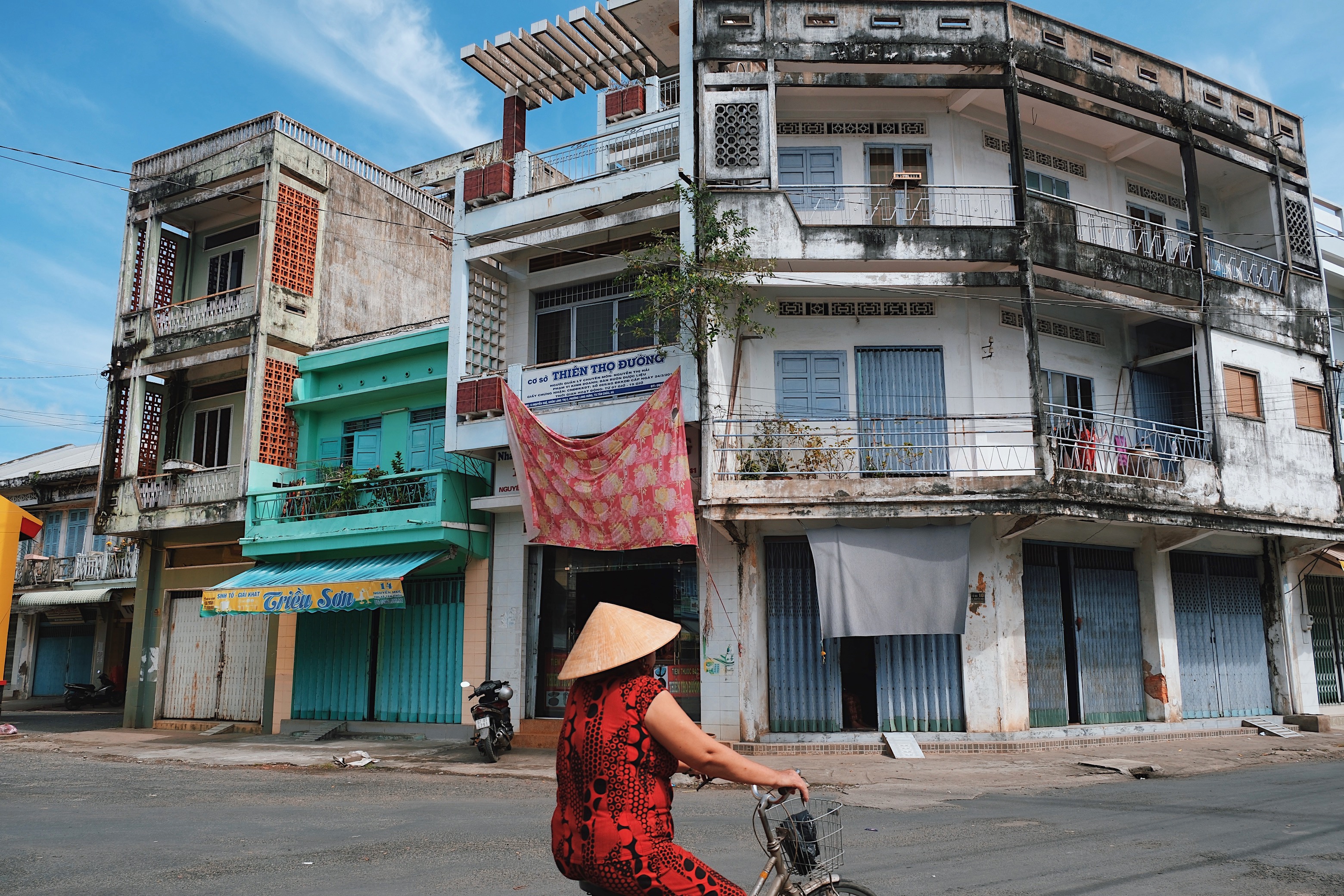 Tropical modernist townhouses in Tan Chau, Vietnam, with expressive façade designs, deep-set windows, and decorative grilles