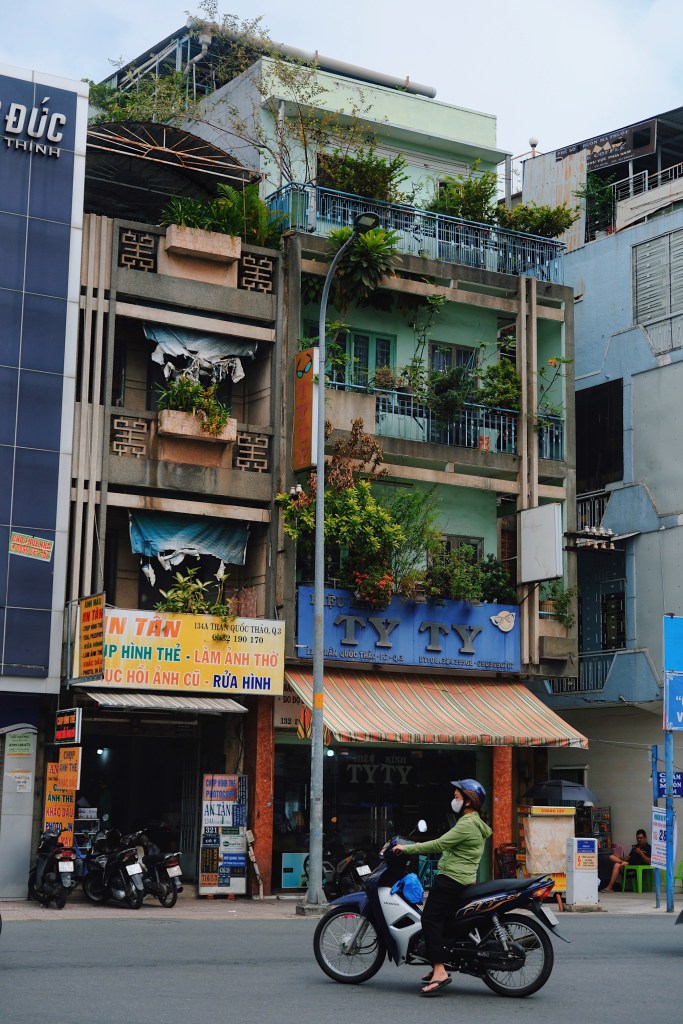 Residential shophouses in Ho Chi Minh City featuring light and airy modernist elements, such as double-wall balconies and vertical louvers, enhanced by Asian-inspired concrete decorative details.