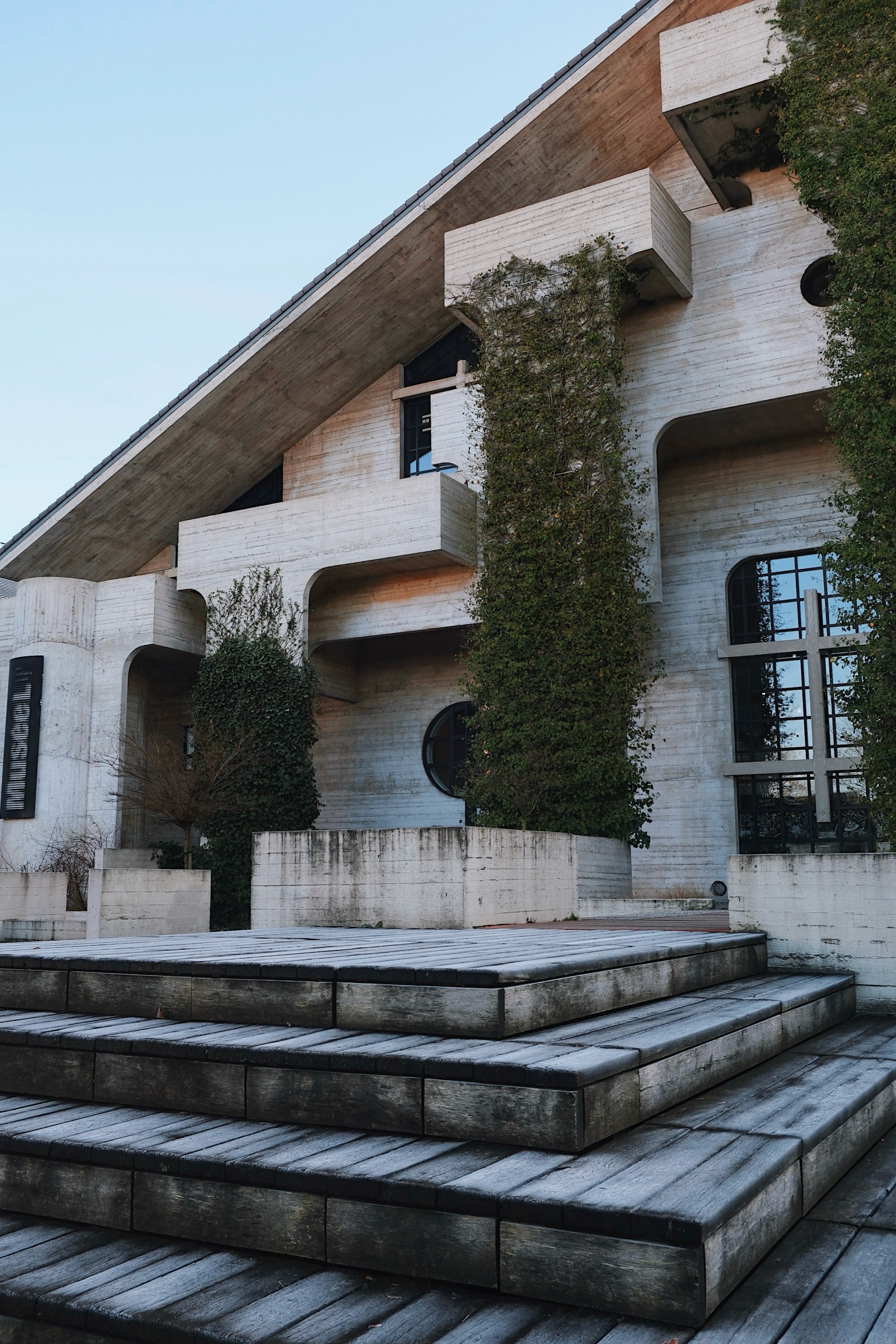 The Ancienne Bibliothèque des Sciences in Louvain-la-Neuve, with cantilevered concrete balconies, climbing greenery, and deep-set geometric windows, exemplifies 1970s Brutalist design.