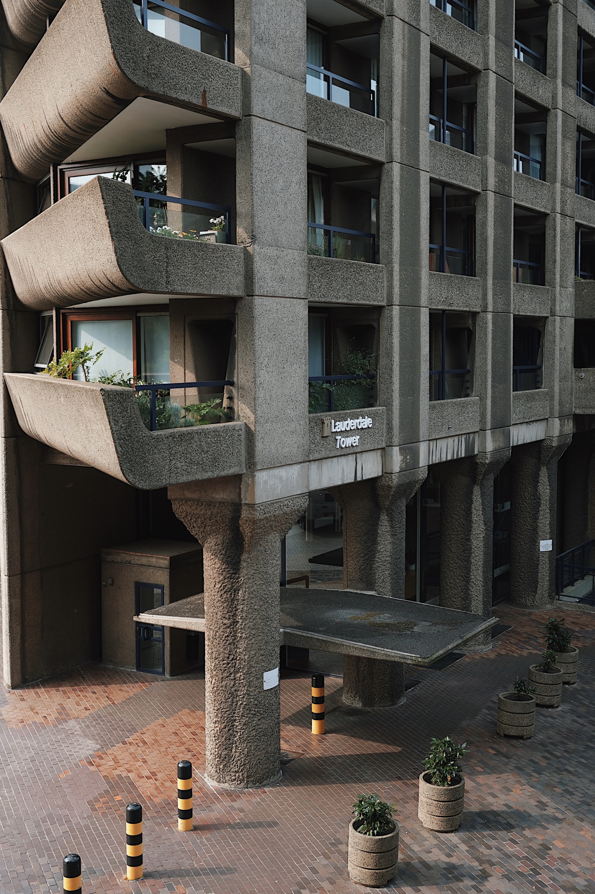 Brutalist residential tower at the Barbican Estate in London, showcasing rough-textured concrete, sculptural balconies, and modular vertical geometry