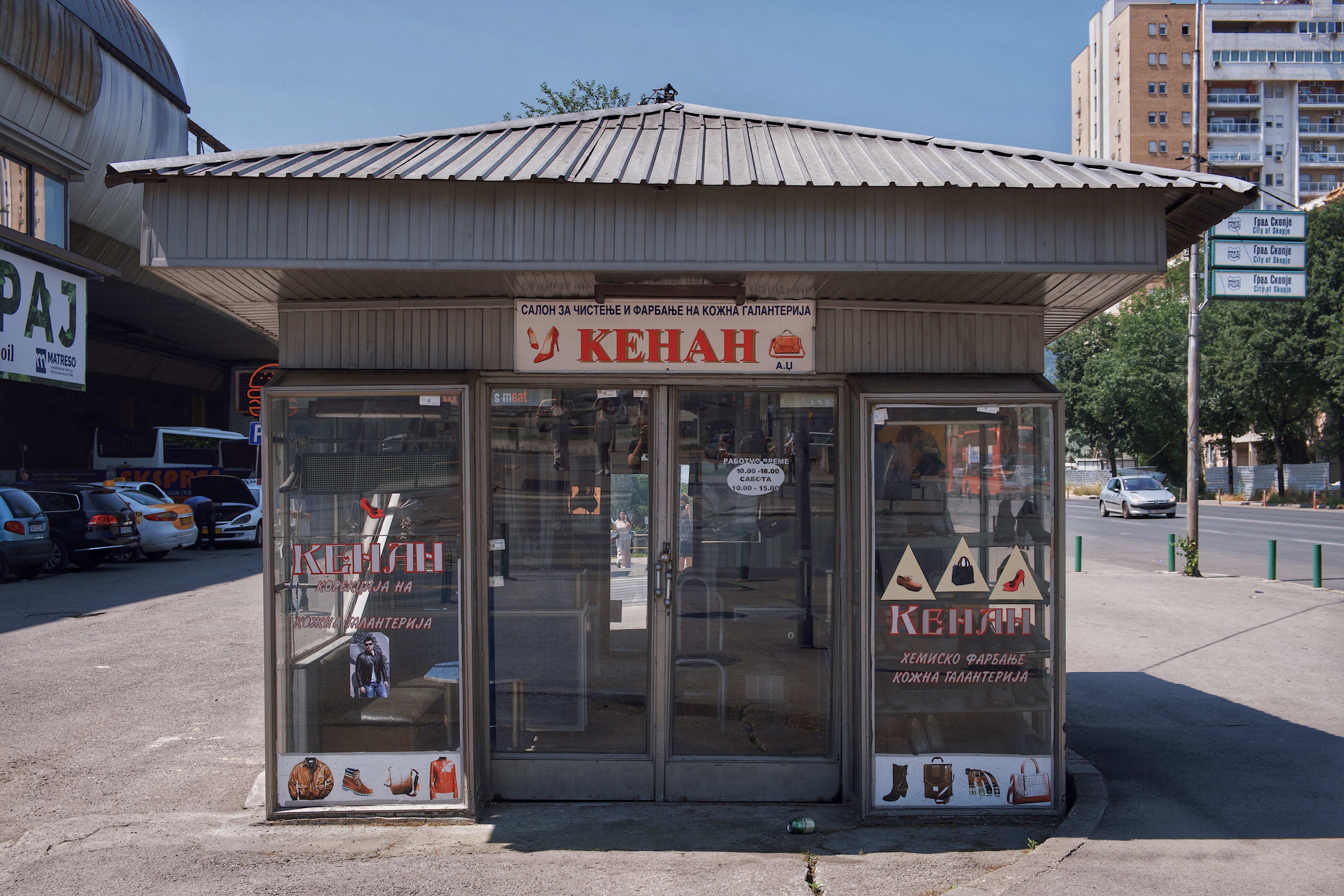 Glass-fronted kiosk at Central Train Station in Skopje, North Macedonia, featuring signage in Cyrillic and surrounded by mid-century modernist infrastructure
