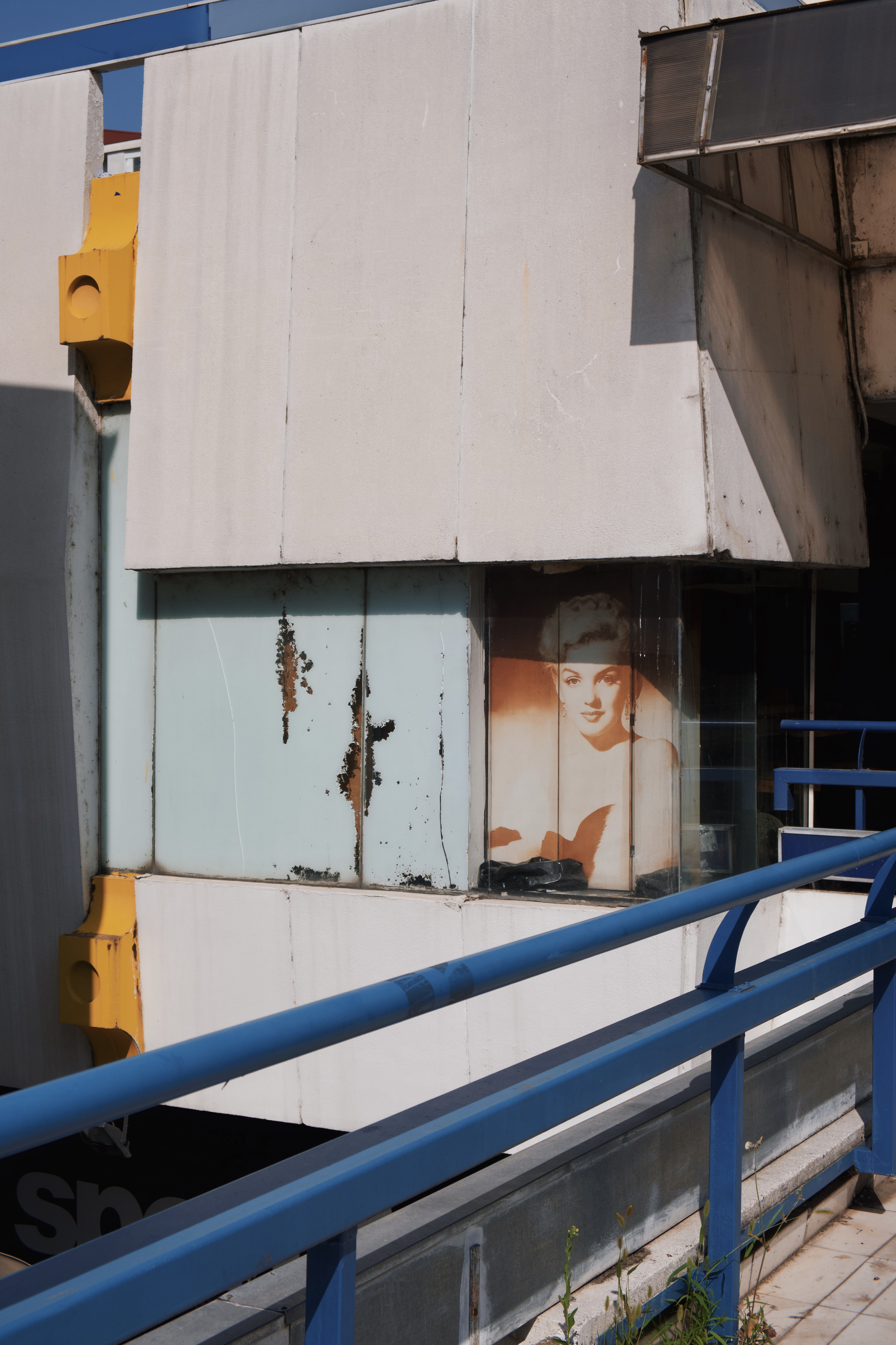 Aging facade at Skopje’s City Trade Center, showing weathered modernist details and a faded 20th-century portrait behind glass